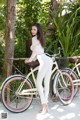 A woman standing next to a white bicycle.