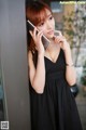 A woman in a black dress talking on a cell phone.