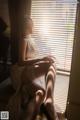 A woman sitting on a window sill in a white dress.