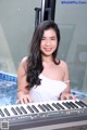 A woman in a white dress playing a keyboard.