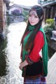 A woman in a red shirt and green scarf posing for a picture.