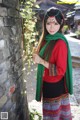 A woman in a red shirt and green scarf posing for a picture.