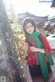 A woman in a red shirt and green scarf posing for a picture.