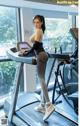 A woman is standing on a treadmill in a gym.