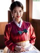 A woman in a red and white hanbok sitting on a bed.