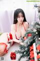 a woman in a red lingerie sitting next to a christmas tree