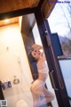 A woman in a white lingerie standing in a bathroom.