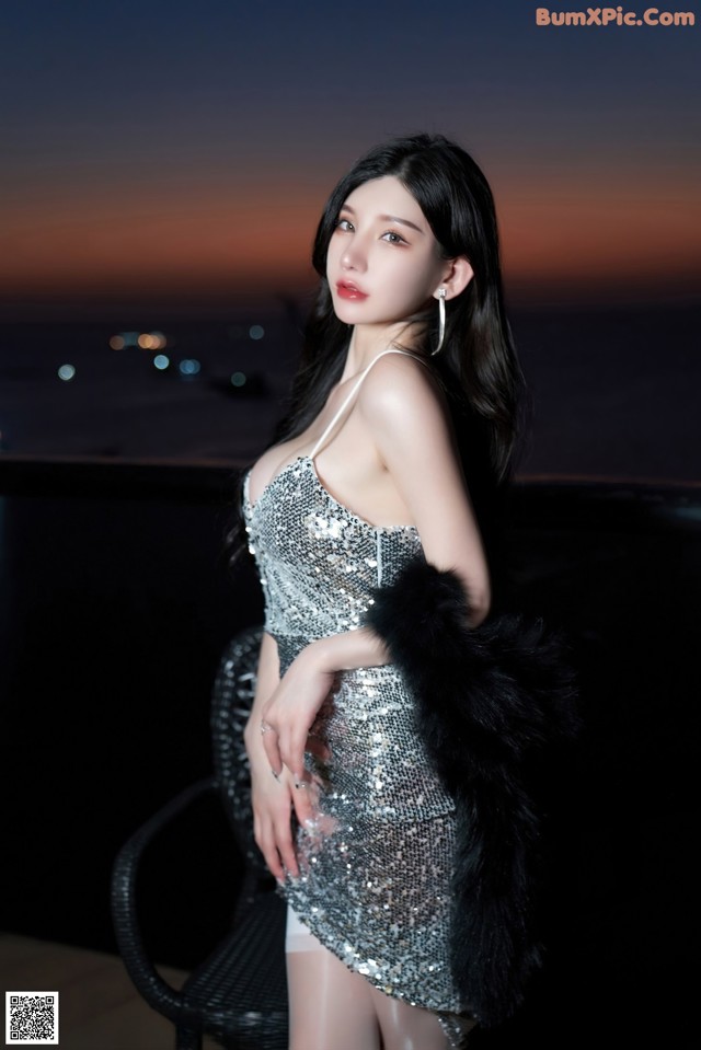 A woman in a silver dress posing for a picture.