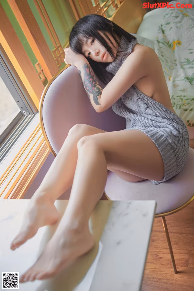 A woman sitting on a chair in front of a window.