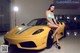 A woman in a bikini sitting on a yellow sports car.