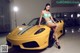 A woman in a bikini sitting on a yellow sports car.