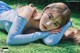 A woman laying on the grass with her head resting on her hands.