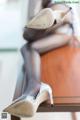 A woman sitting on top of a wooden table wearing high heels.