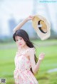 A woman in a pink dress holding a straw hat.