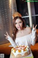 A woman wearing a crown and holding a birthday cake.