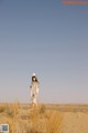 A woman standing in the middle of a desert.