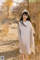 A woman standing in the sand next to a tree.