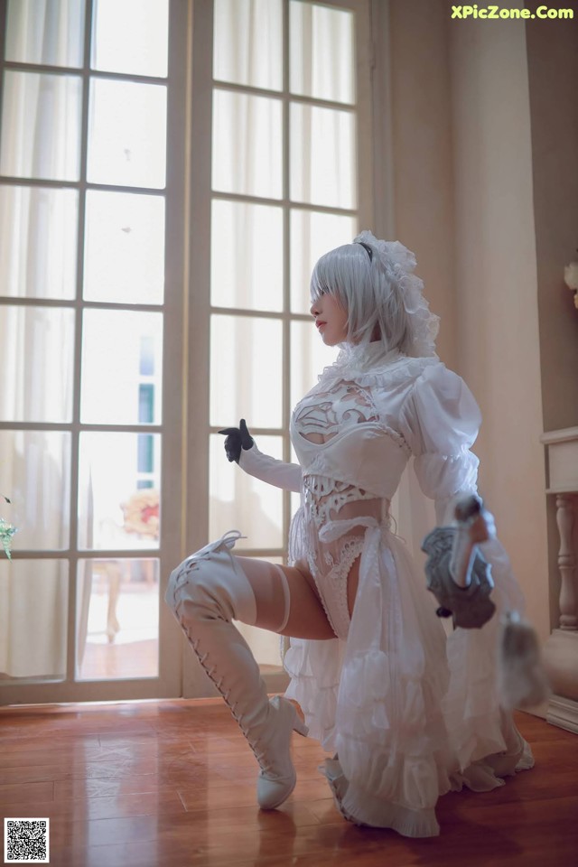 A woman in a white dress and thigh high boots posing for a picture.