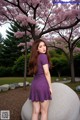 A woman in a purple dress standing on a rock.