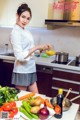 A woman in a kitchen preparing food on a table.