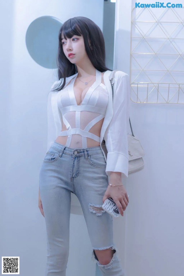 a woman in a white top and jeans posing for a picture