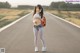 A woman standing on the side of a road with a backpack.