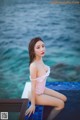 A woman in a pink bathing suit sitting on the edge of a pool.