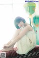 A woman sitting on top of a bed next to a window.