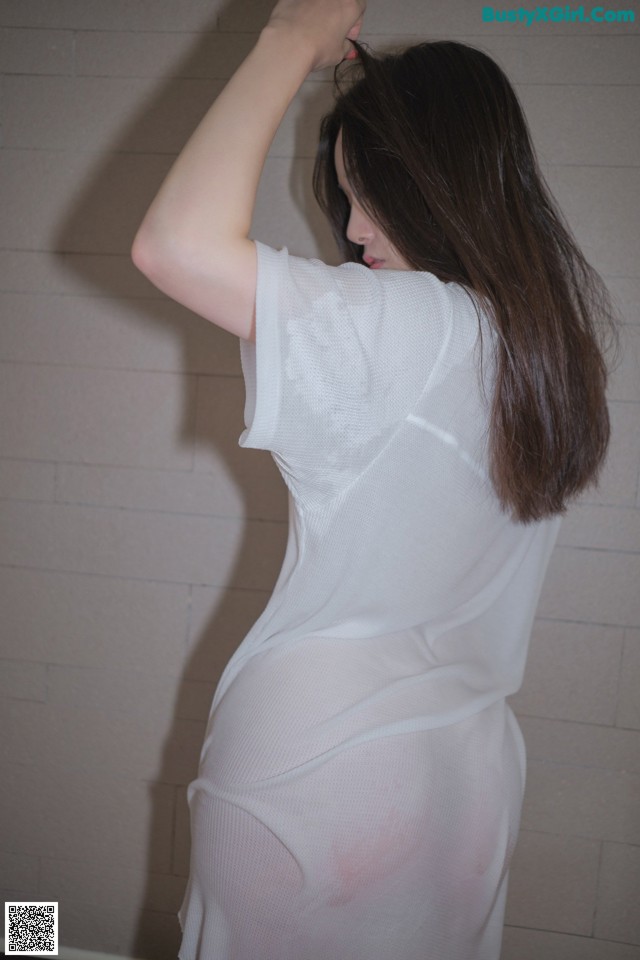 A woman in a white shirt is standing in a bathroom.