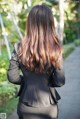 A woman in a black suit standing on a sidewalk.