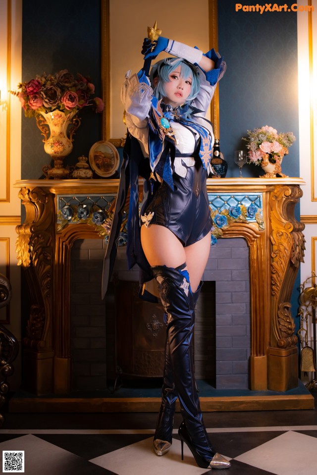 A woman in a blue and black outfit posing in front of a fireplace.