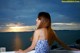 A woman in a blue and white dress looking out over the ocean.