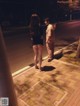 A man and a woman standing on a sidewalk at night.