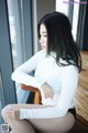 A woman sitting on a chair in front of a window.