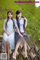 A couple of women sitting on top of a wooden bridge.