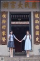 Two young women holding hands in front of a building.