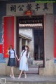 A couple of women standing next to each other in front of a building.