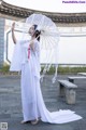 A woman in a white dress holding an umbrella.